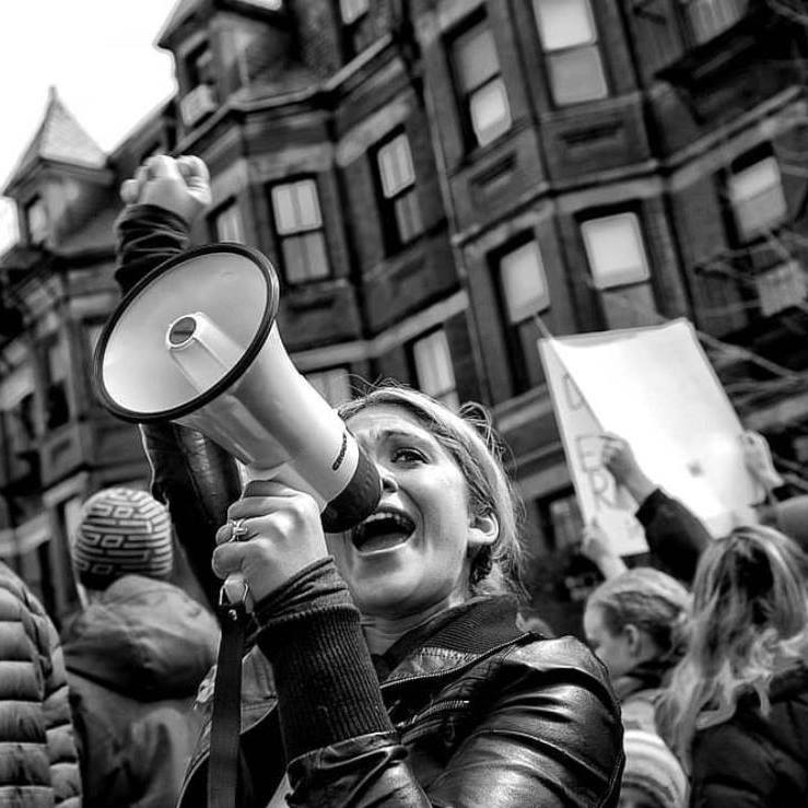 Black and white photo of student in downtown Boston at a rally with a megaphone