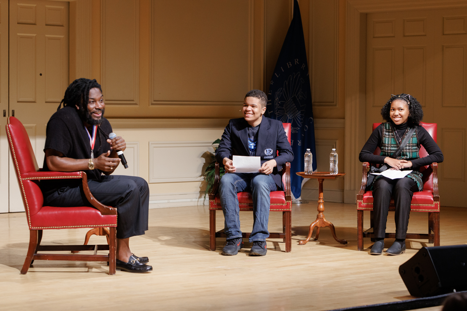 jason reynolds and two teenage students on a stage