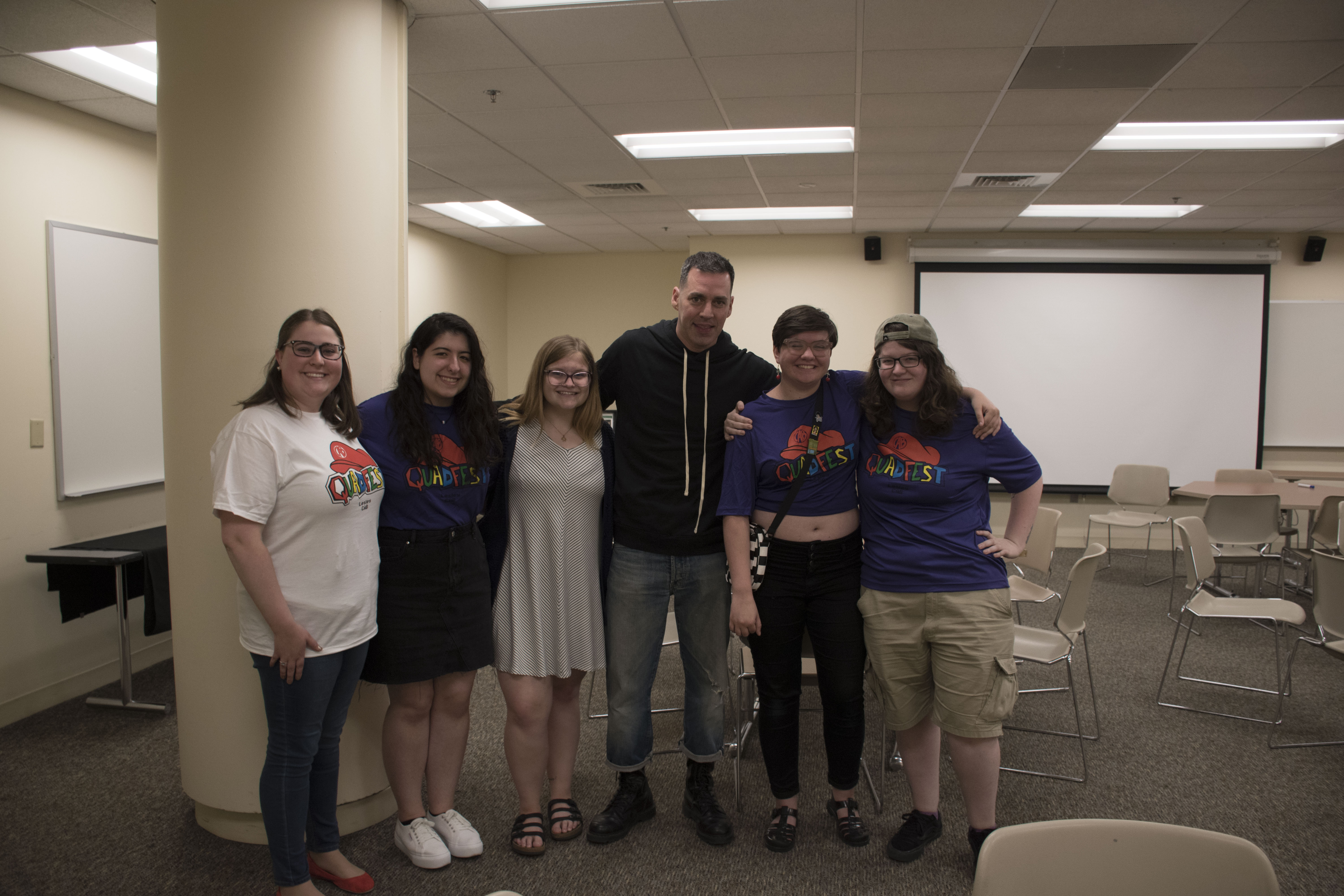 Photograph of 5 students posing with comedian John Roberts.
