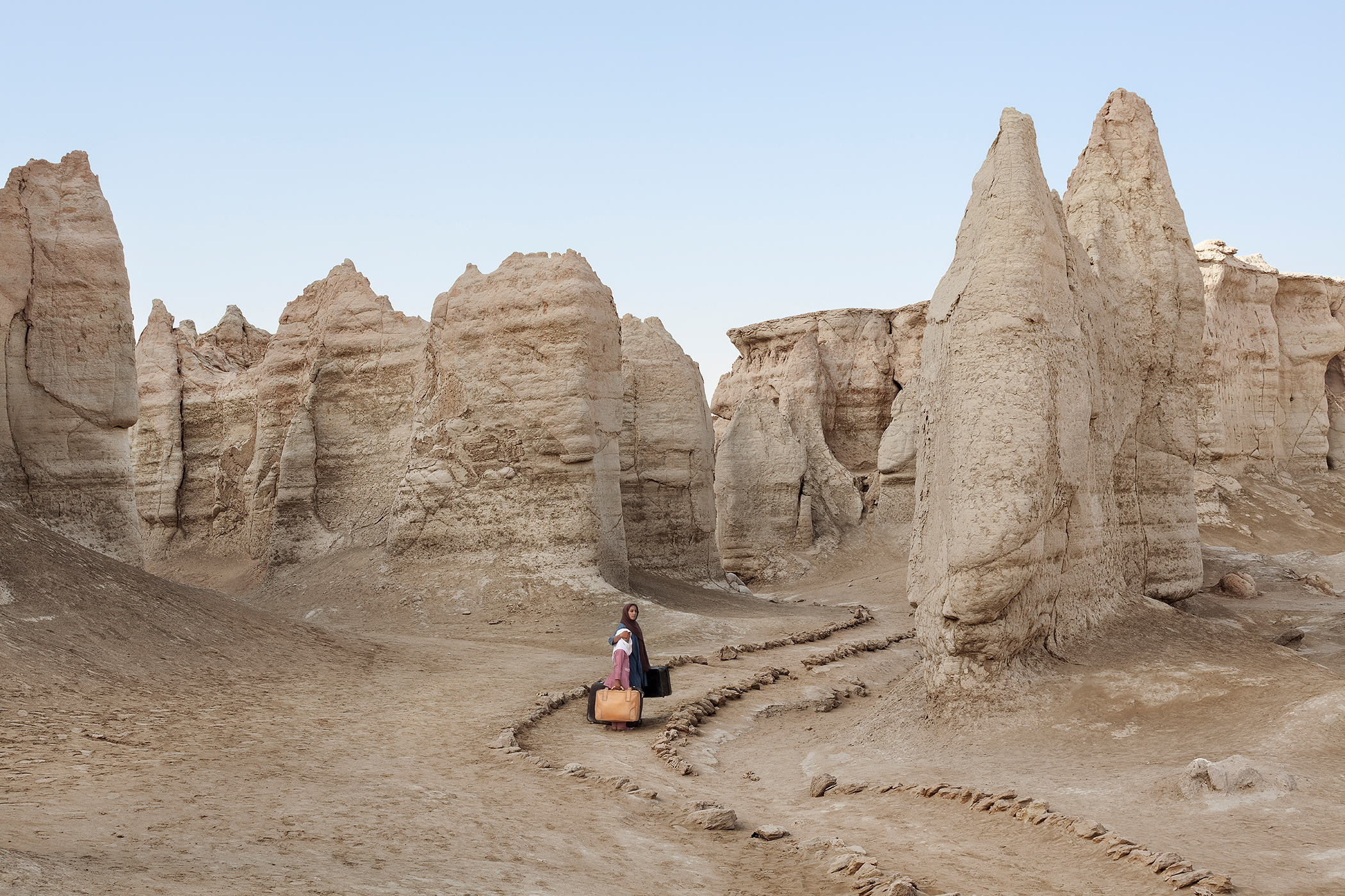 two people with suitcases walking through the desert