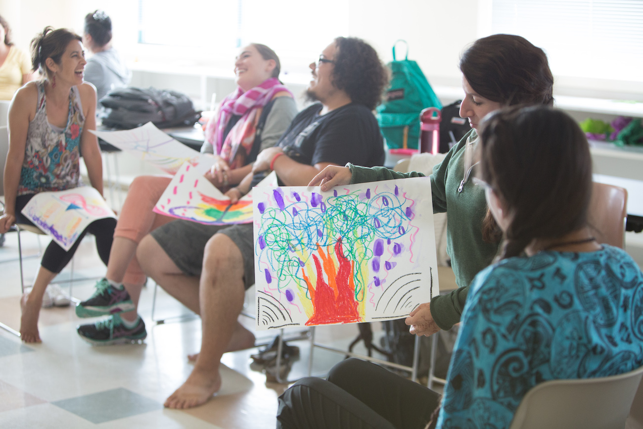 students sitting in chairs holding up drawings