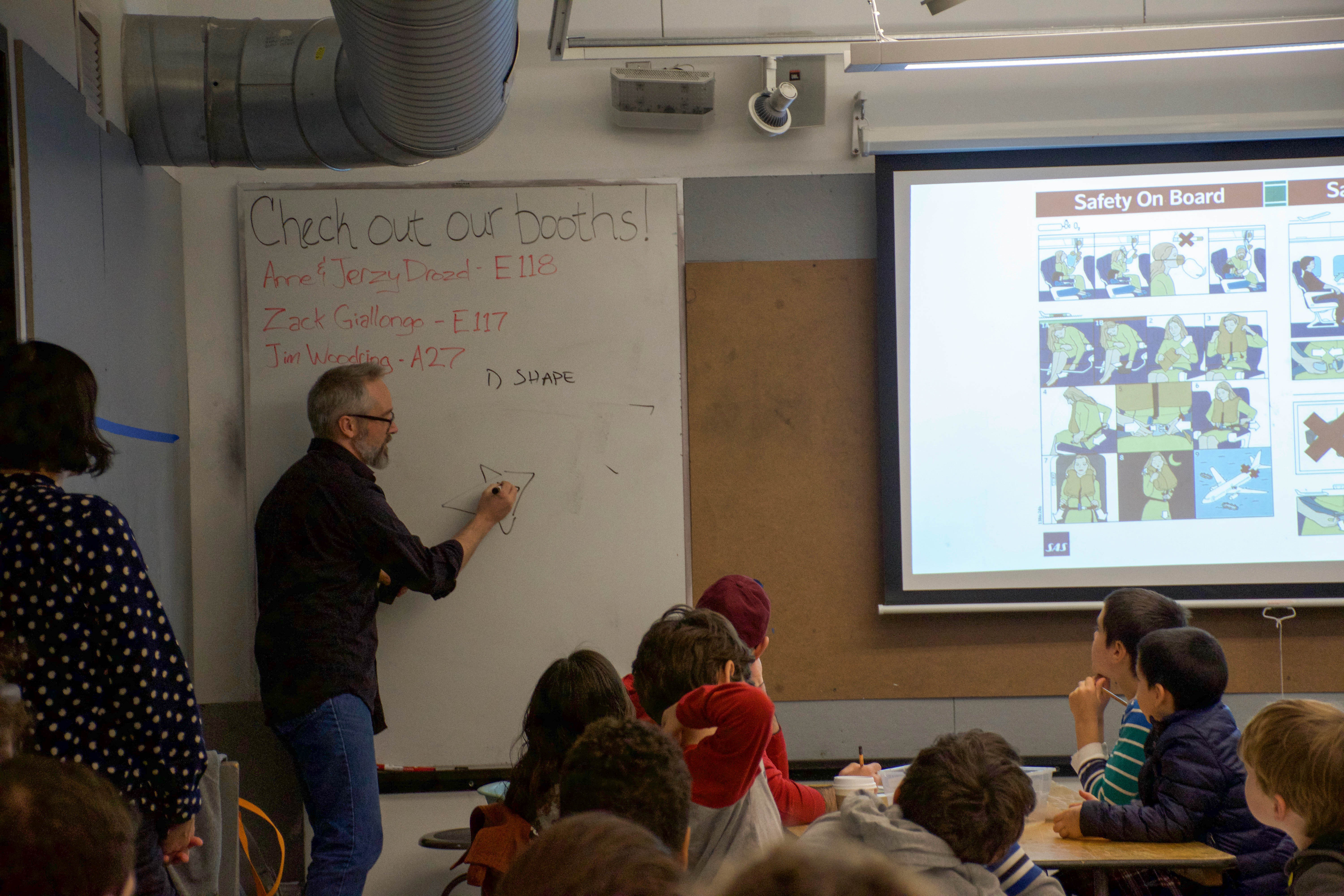 A man presenting a workshop on how to draw comics in front of a screen