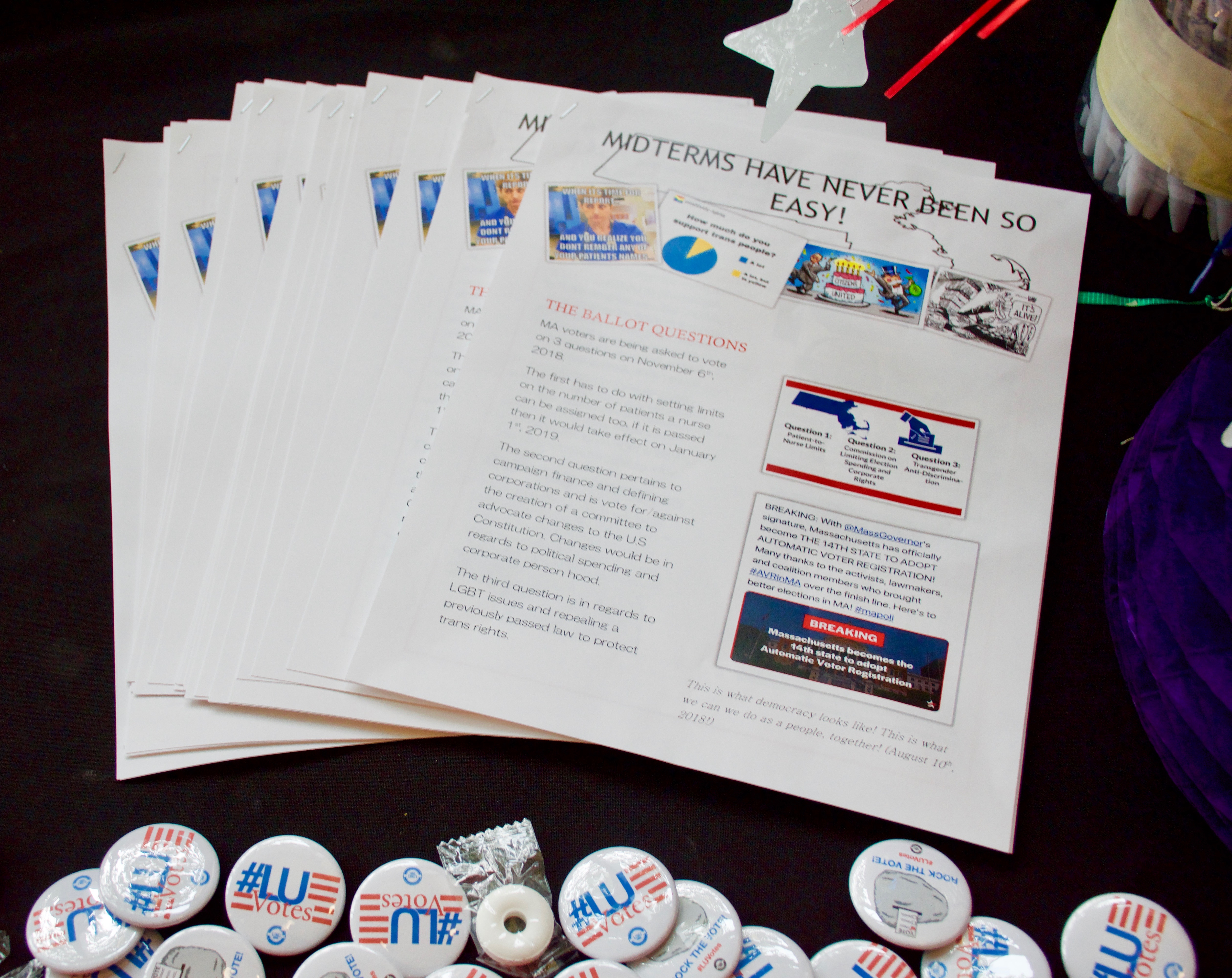 Voter registration information with fliers and buttons on a table.