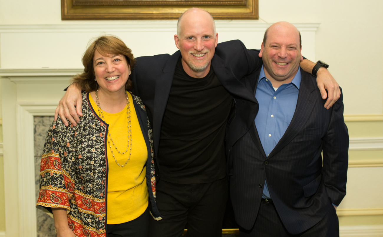 Paul Nicklen stands between Gerri and Jeff Weiss with his arms around them.