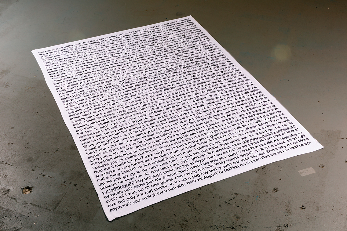white blanket on concrete floor with black text from private messenger printed on blanket 