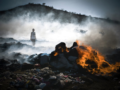 person stands at the bottom of the hill around rocks and a fire