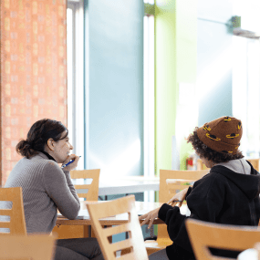 Two people speak at a table in Washburn dining hall.