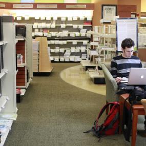 student using laptop in bookstore 