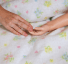 photo of adult hand touching a small doll's hand on a child's blanket