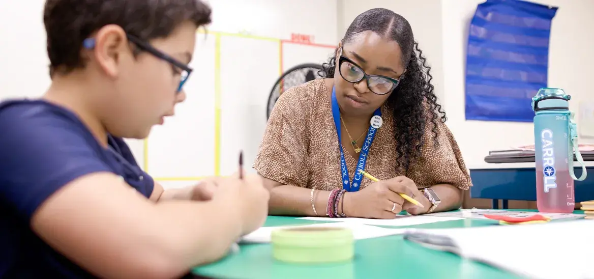 Teaching sitting with student writing at round table