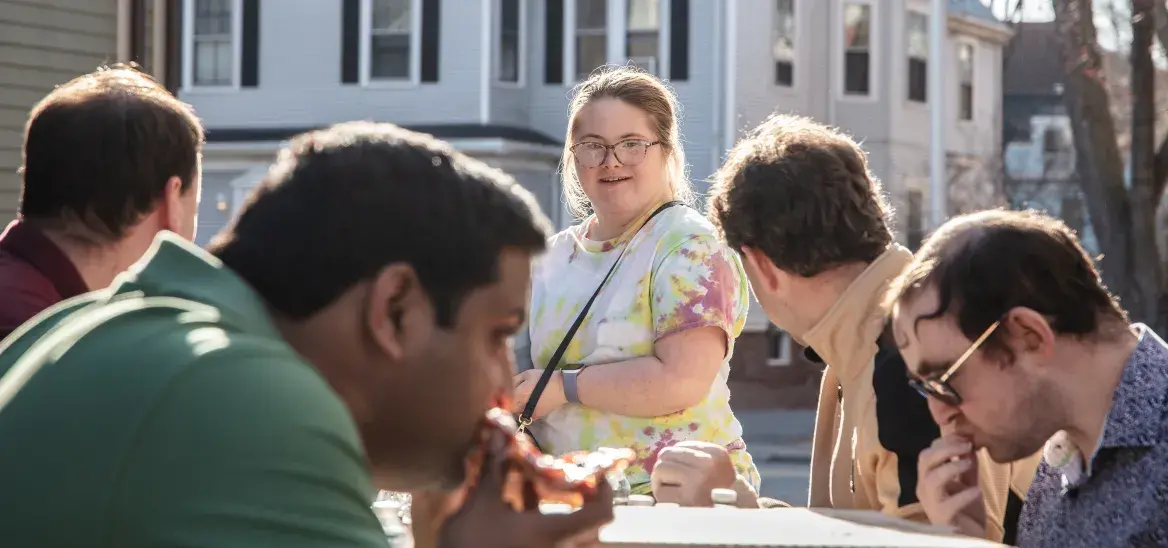 Students sitting around an outdoor table with pizza