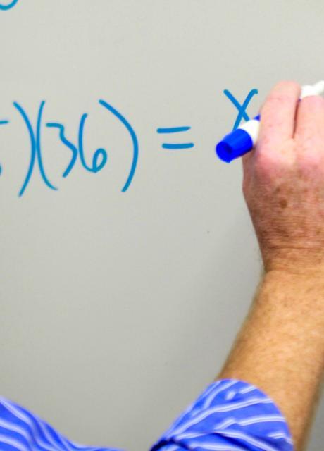person writing formula on white board