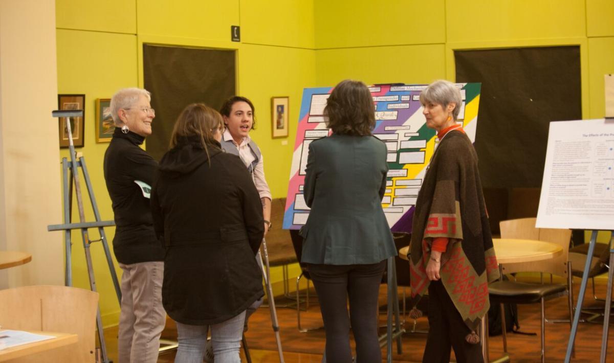 Group of people discussing poster presentation in atrium