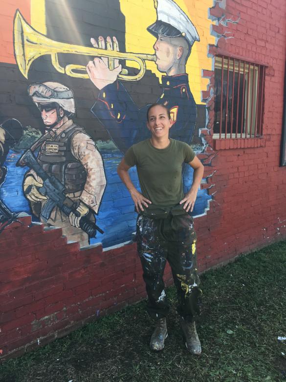 McKelvey stands in gront of a mural she painted on a wall for Marine Week Detroit in 2017.