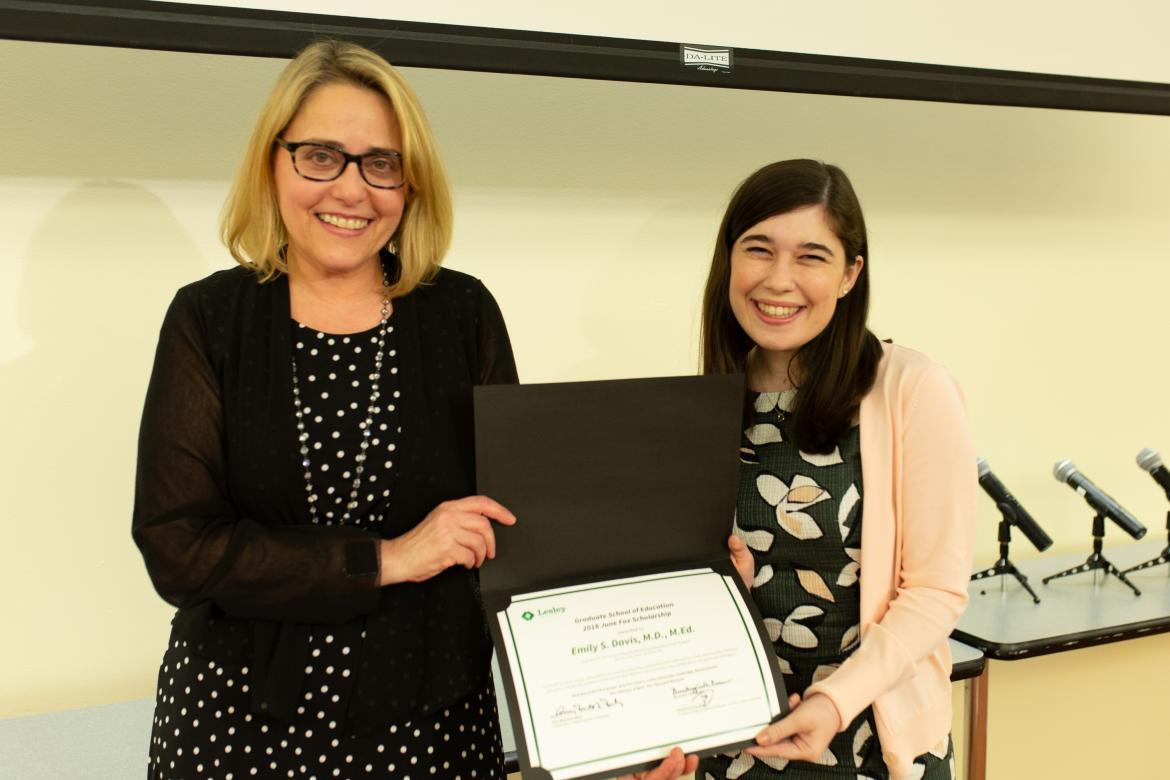 Amy Rutstein-Riley and Emily Davis smile for the camera while jointly holding up Emily's award certificate