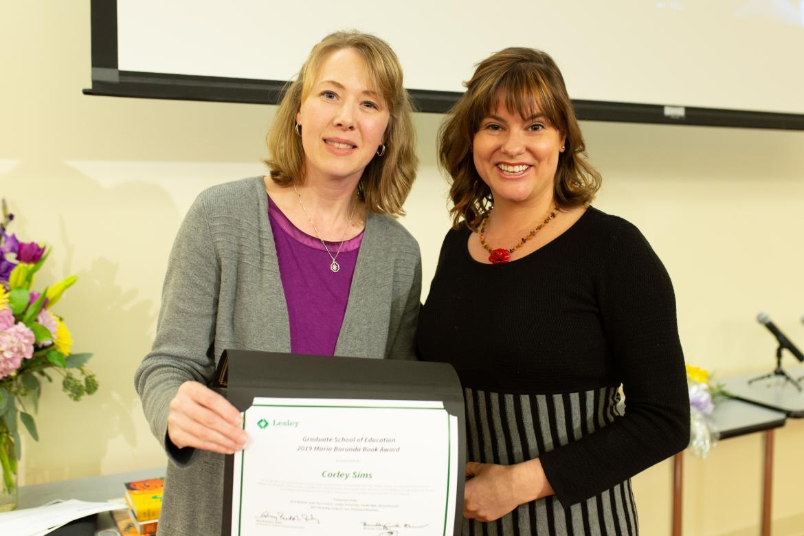 Erika Dawes and Corley Sims pose for the camera while jointly holding up Corley's award certificate.