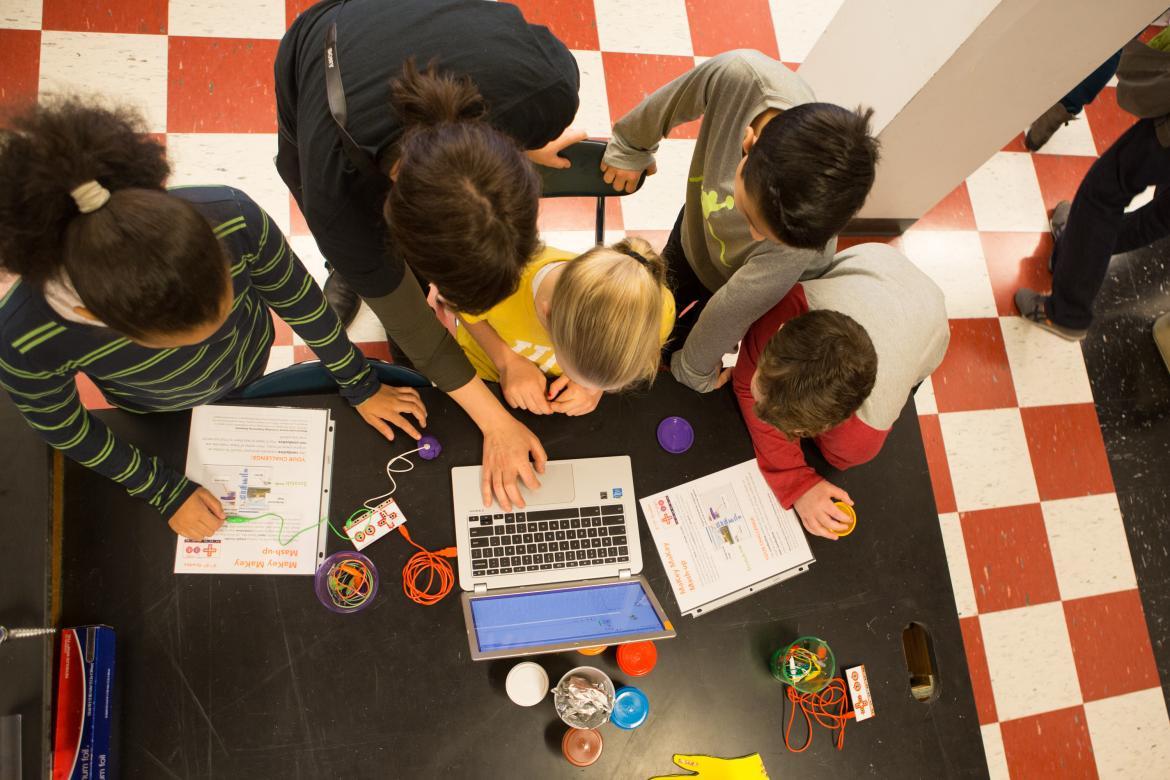 Students crowding around a computer, finalizing their coding project