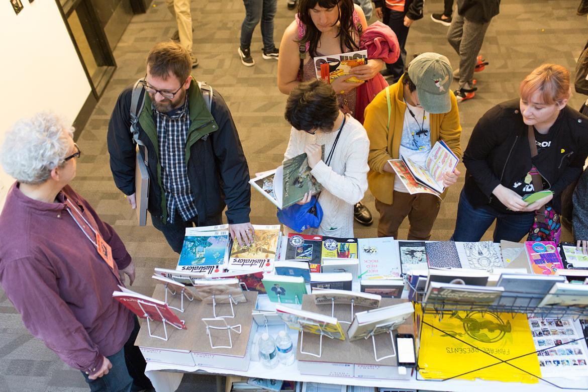 Guests browsing and looking at artwork and comic books at convention at Lesley