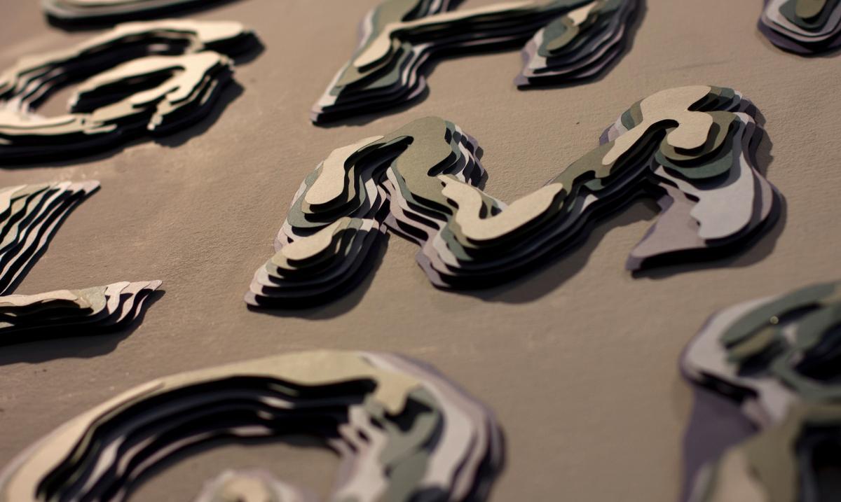 layred wooden letterforms mounted on a brown wall