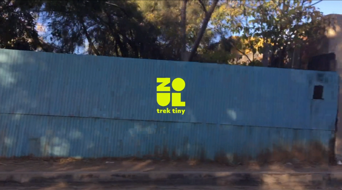 video still of trees and blue wall with bright green text over it 