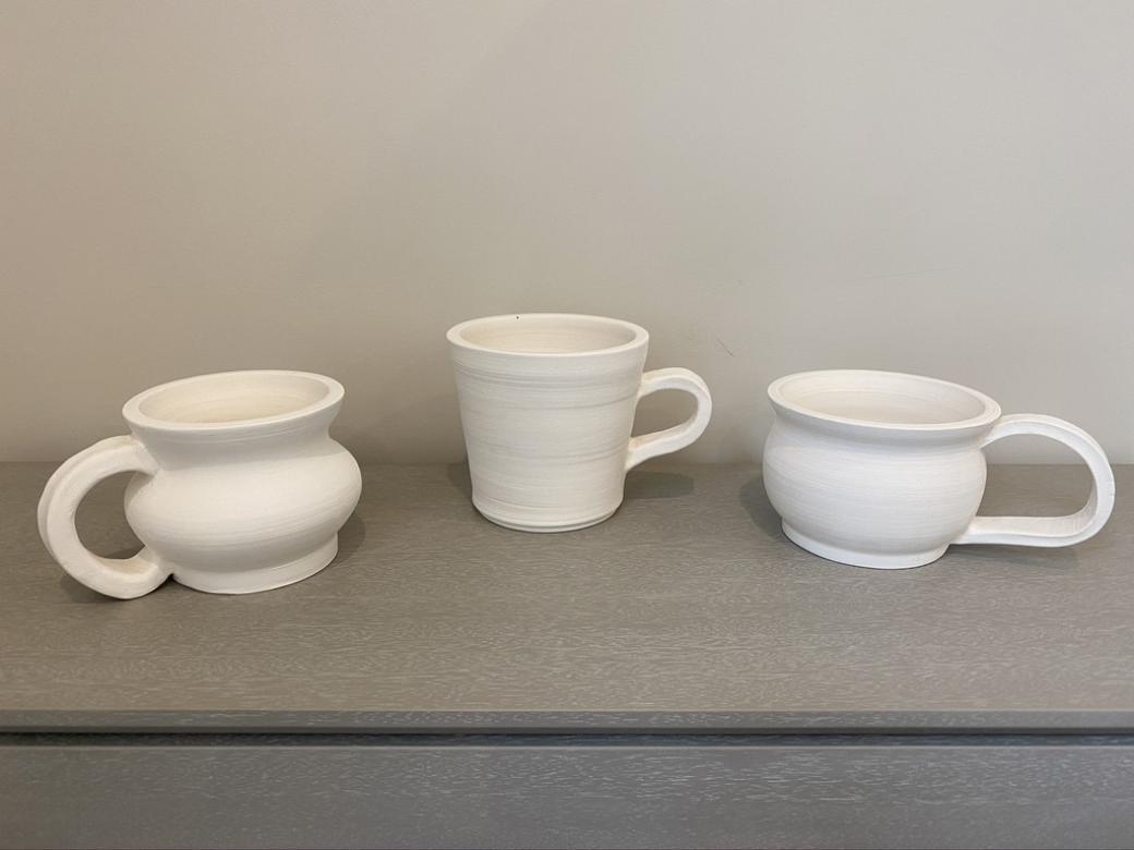 Three unfinished mugs made from stoneware clay.