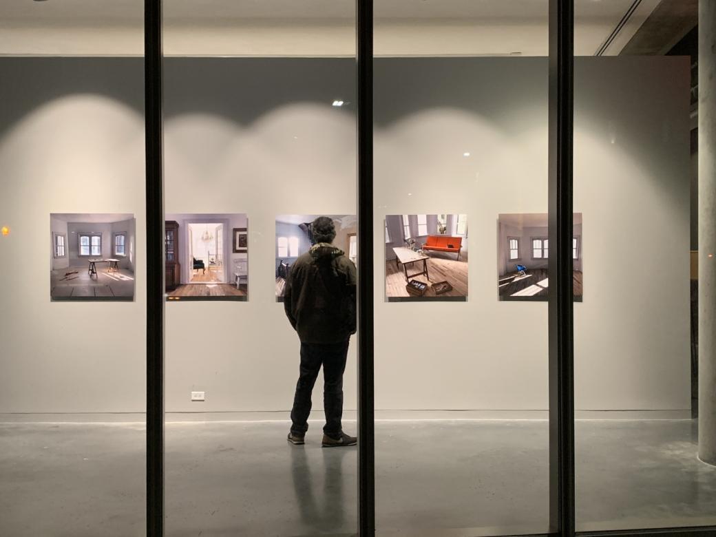 man in gallery looking at art hanging on wall