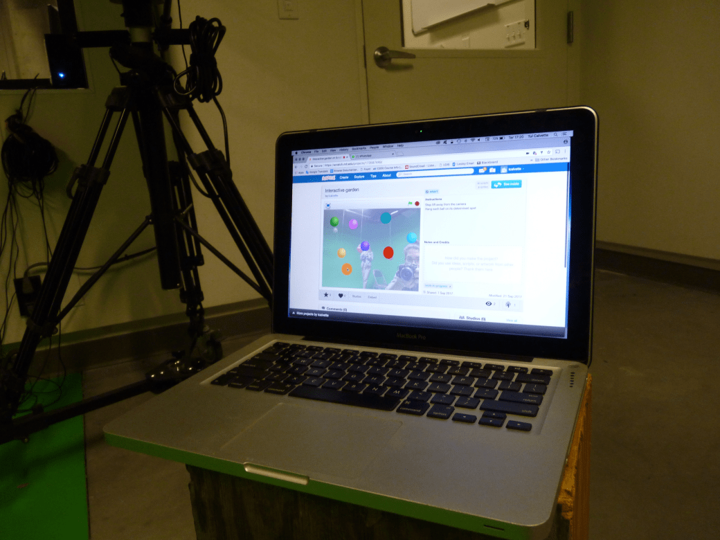 Close up of a laptop with the Scratch program. Colored balls can be seen on the screen as part of the program with the title "Interactive Garden" above them.