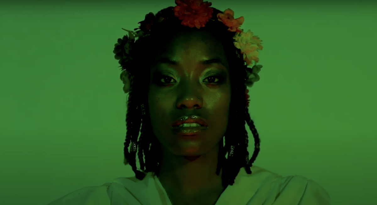 Green-filtered close up of a woman wearing a flower crown.