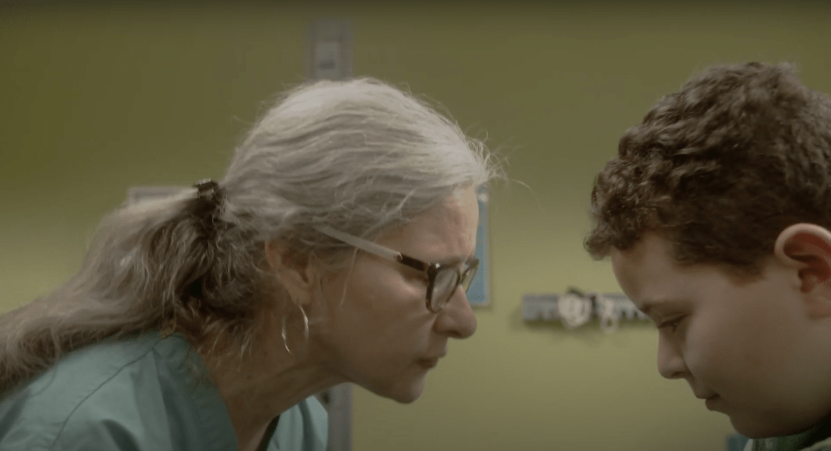 Elderly woman with gray hair looks down at a young boy. 