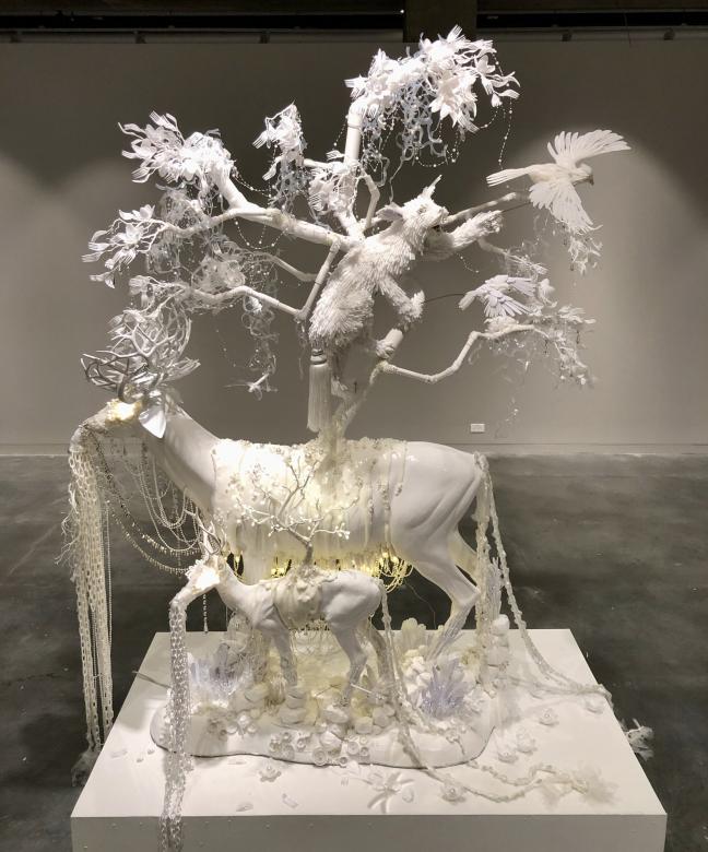 A white sculpture of forest animals made from plastics like plastic utensils. 