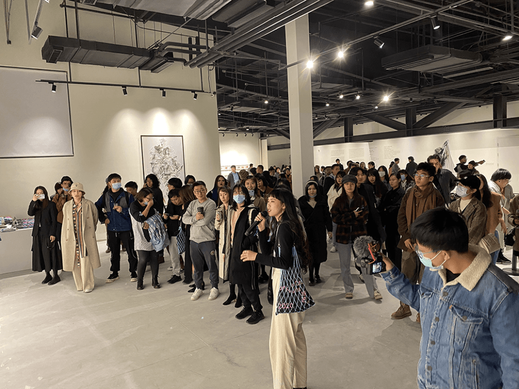 An audience at the exhibit "A Crop of Fruits" listening to someone speak over a microphone. 