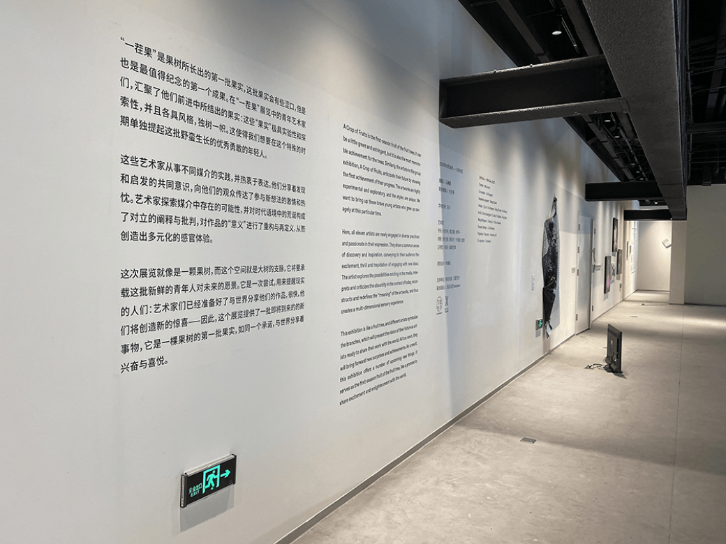 This is writing on the wall of the exhibiton "A Crop of Fruits" that introduces the exhibit and artists. There is writing in both English and Chinese. 