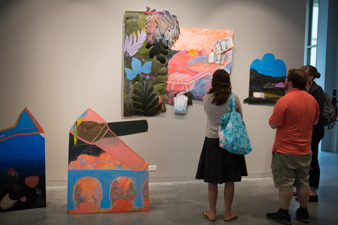 Three people looking at artwork on a gallery wall.