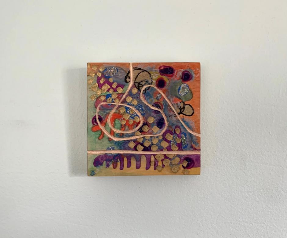 A square art piece featuring different organic shapes, circles, and curves in orange, deep purple, indigo blue, and light green watercolors. Some circles are added in black outlined marker. Some circles are painted with gold glitter. Across the piece a carved beige squiggle works its way across the surface.