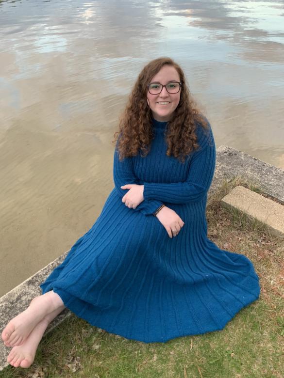 kiera rowe sitting in front of lake in blue dress