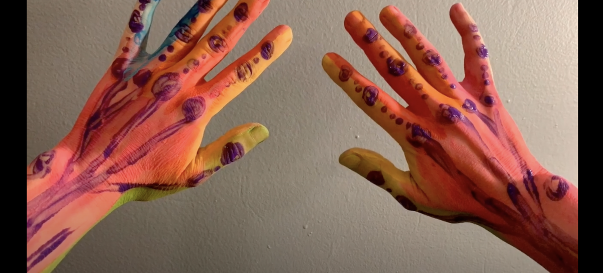 Photo of hands painted with bright colored tempera paints. 