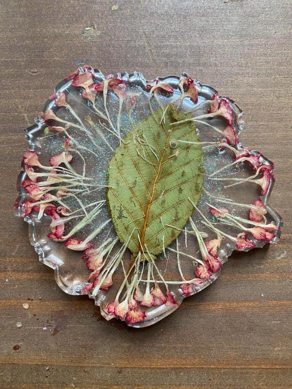 leaf and dried flowers hardened in clear liquid into a coaster