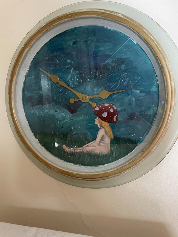 photo of a clock with a girl in a field painted onto it