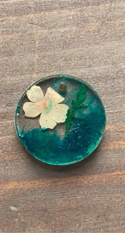 circular charm with turquoise and a flower inside