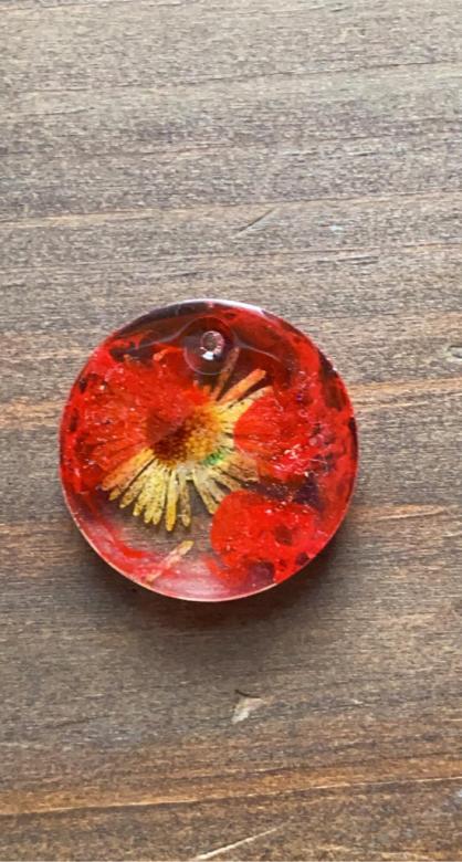 circular red charm with yellow flower