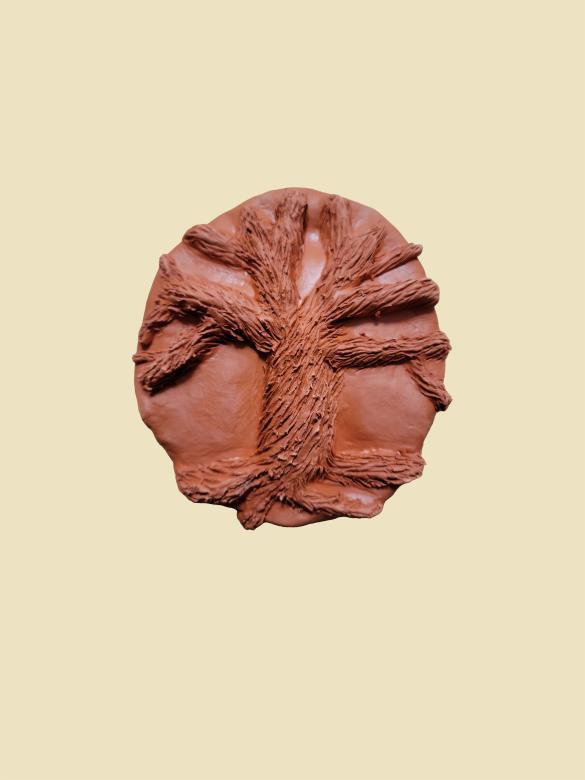 A brown piece of clay with a tree carved out of it showing a textured trunk. The tree has no leaves.
