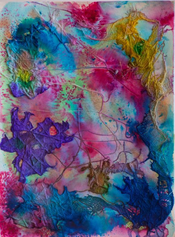 A background of mainly pink and blue with green and orange also mixed in. Overlaid on top of this background are several pieces of fabric all connected by a string that loops around through the center of the piece. All the fabric is painted with vibrant blue, yellow, and purple colors and the various sections line the edge of this piece. The fabrics in clue mesh, cheesecloth, and thing stringy textures.