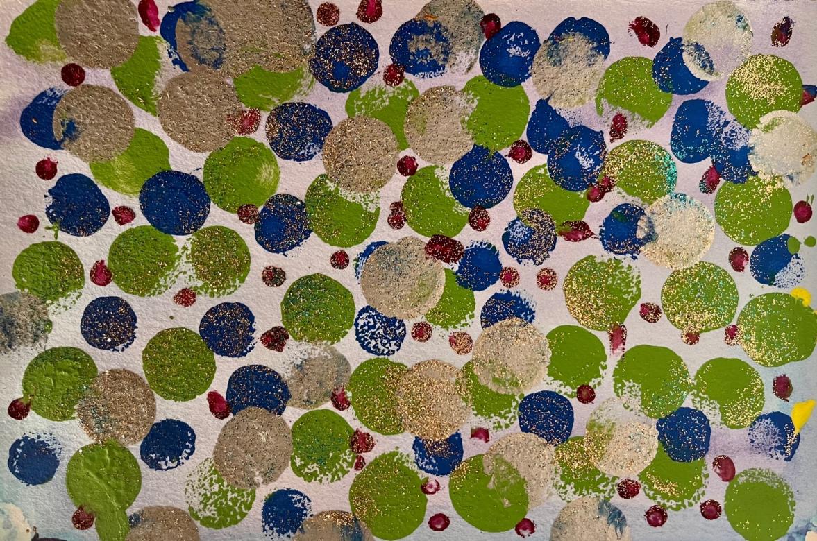 Painting: The background is white with faint hints of light blue and purple. Painted on this background are circles of various sizes in the colors silver, green, blue, and red. The green, blue, and silver circles are all about the same sizes. The red ones are much smaller and are scattered around and in between the other circles. All the circles have various amounts of gold glitter on them. On the far-right side of the piece are two small splotches of yellow paint. 