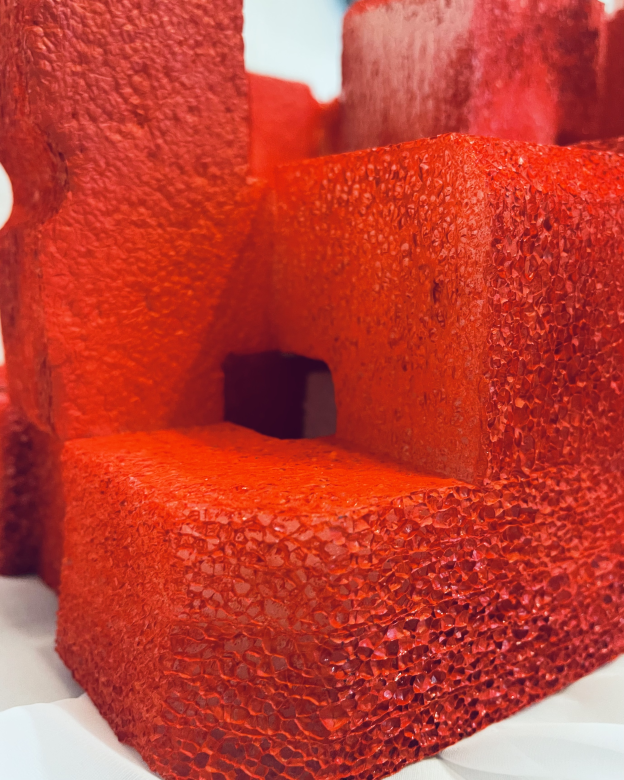 Close up of the red sculpture "Puzzled", the foam red texture of the sculpture is seen up close showing the levels of height within the sculpture.