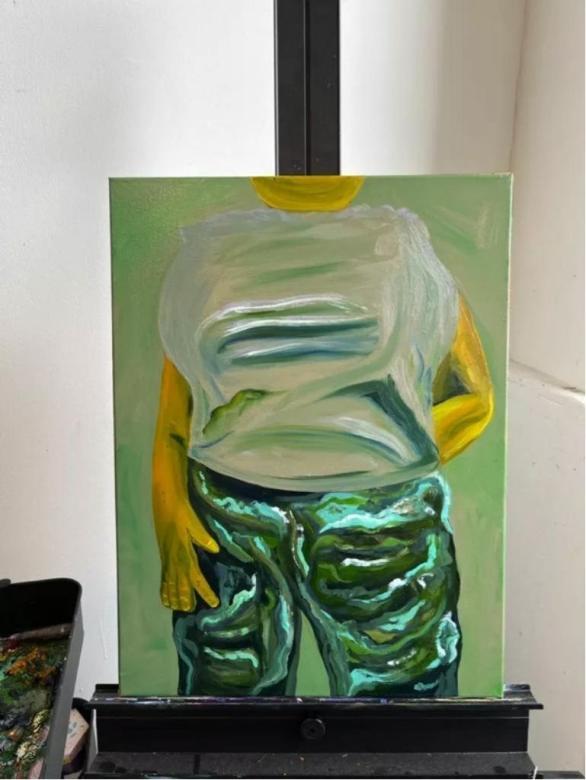 Photo of a canvas with a human body painted wearing white shirt and green pants