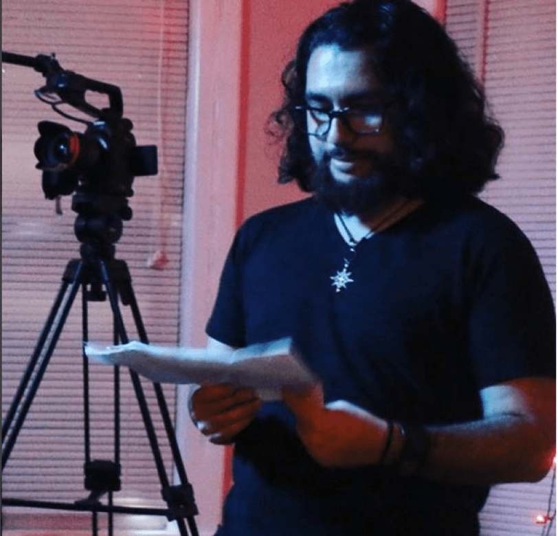 student Adam Holguin reads a script behind the scenes on set