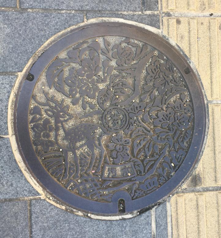 Manhole cover with flowers and a deer.
