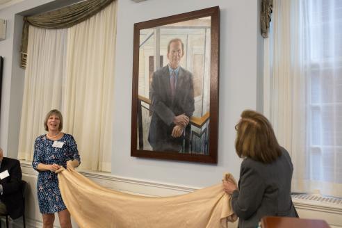 Beth Chiquoine and Deborah Raizes pull down a cloth to unveil the portrait.