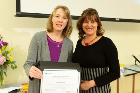 Erika Dawes and Corley Sims pose for the camera while jointly holding up Corley's award certificate.