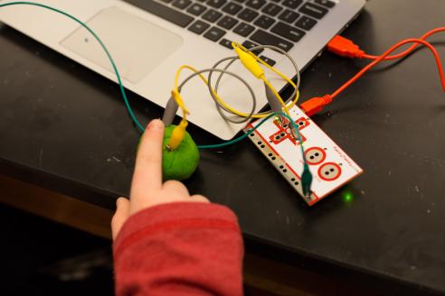 Young student completing a experimental circuit with their finger